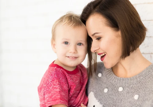 Mãe segura filho no colo enquanto ele sorri